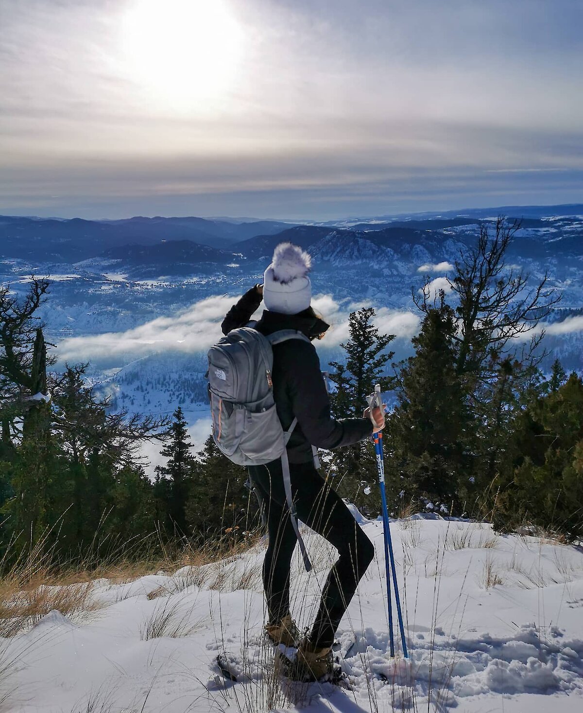 A snowshoer admiring the snow-covered Thompson Valley from Harper Mountain near Kamloops, BC.