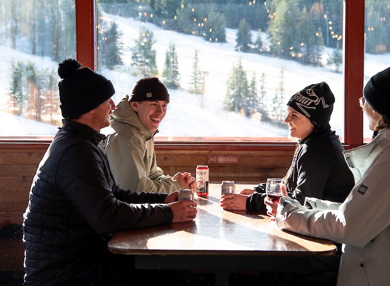 A group of friends enjoying a beer in the cozy Harper Mountain Lodge near Kamloops, BC.