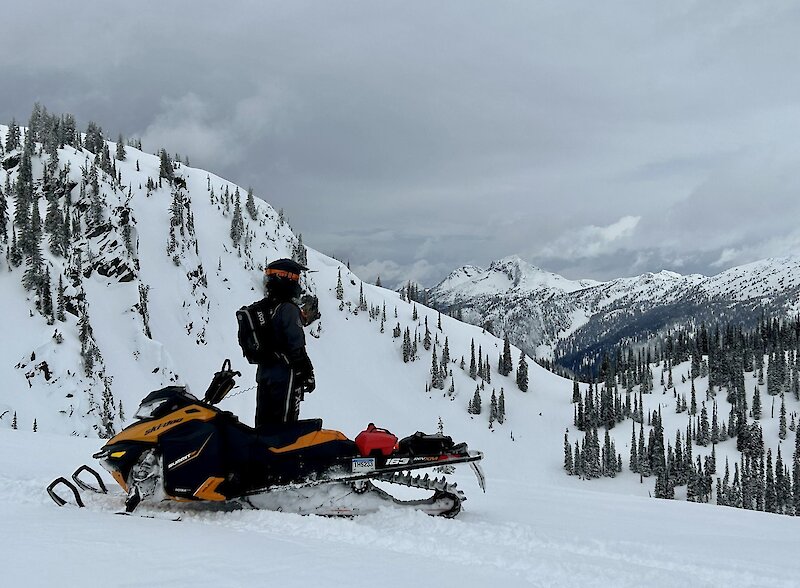 Snowmobile rider admiring the view of the snowy landscape while out exploring in the Thompson Valley, BC.