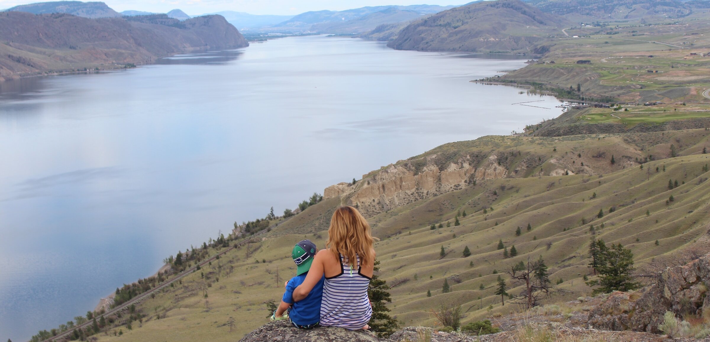 A Mother and son admiring the view over Kamloops Lake from a hiking viewpoint in Kamloops, BC.