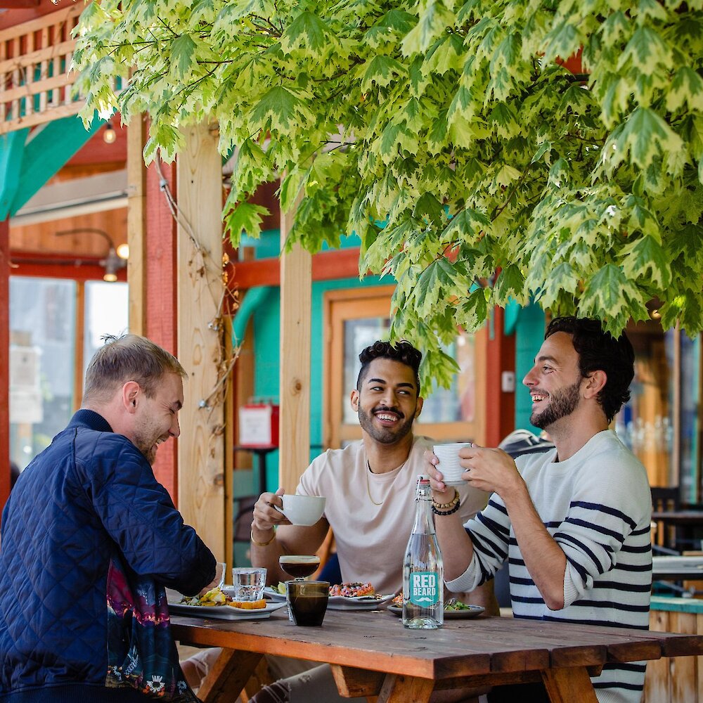 Three people eating at an outdoor patio restaurant table in Kamloops.