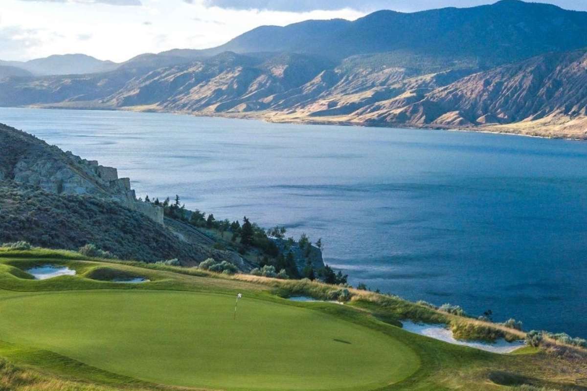 A stunning view of a the Tobiano golf course perched above Kamloops Lake with mountains in the background.