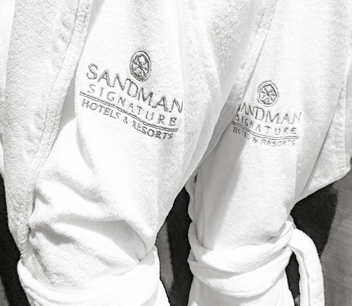 Two white robes with the logo of Sandman Signature Hotel
