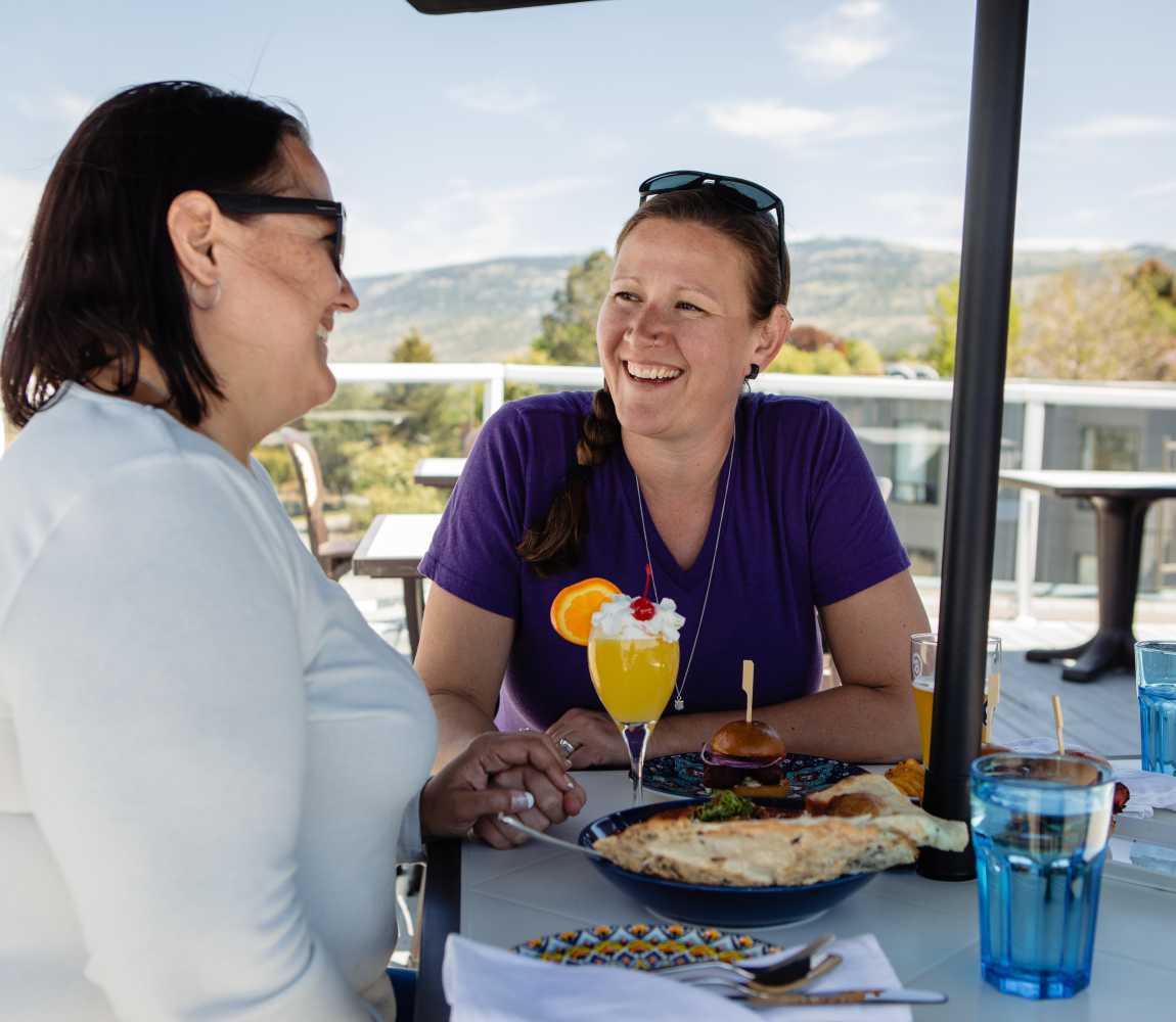 A couple enjoying their meal on the Jadoo Restaurant rooftop Patio lounge that serves Eclectic Modern Indian Cuisine and Craft Cocktails in Kamloops, British Columbia.