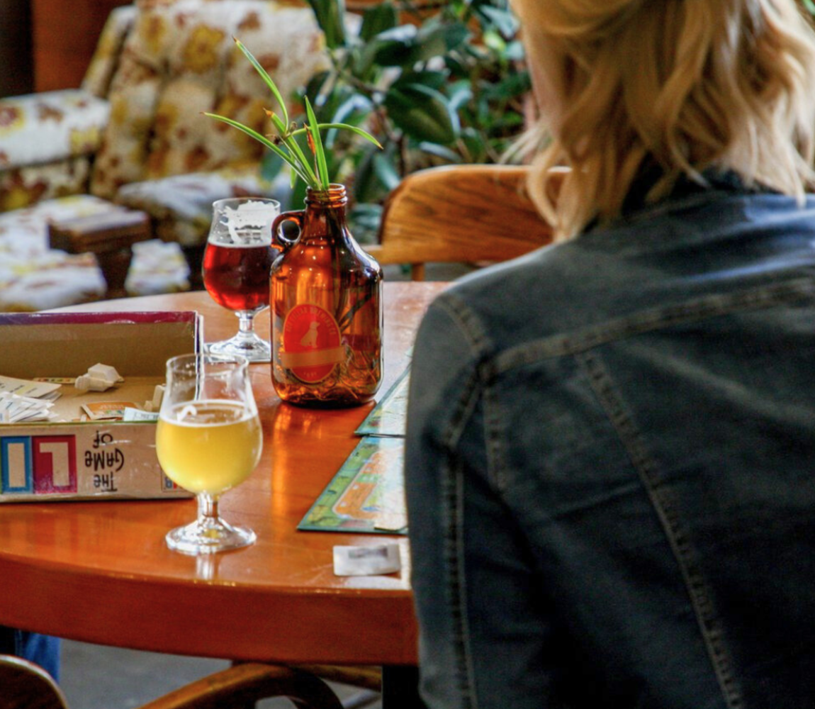 A women drinking a pint of local craft beer and playing a board game at Red Collar Brewing in Kamloops, British Columbia.