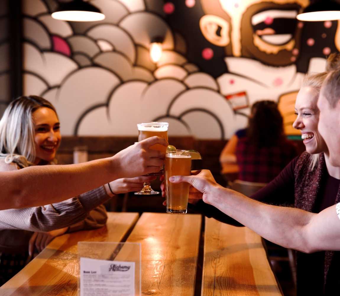 Group of people toasting their craft beers at Alchemy Brewing in Kamloops, BC.