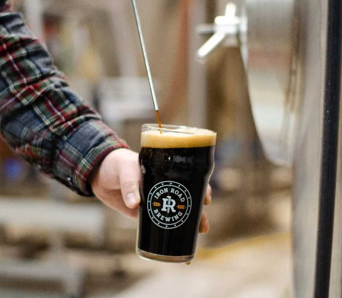 Brewer pouring their Iron Road Porter from the tank at Iron Road Brewing in Kamloops, BC.