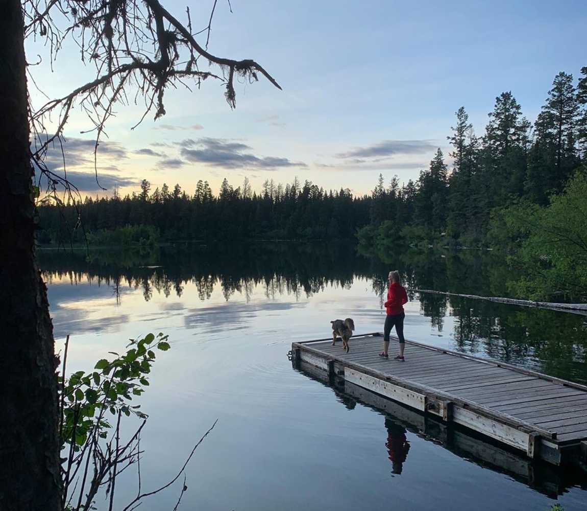 person standing on dock overlooking a lake at sunset