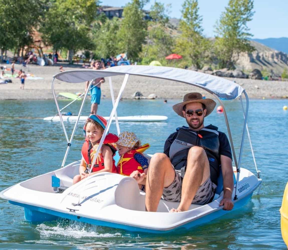 Father and his kids enjoy a paddle boat on Kamloops lake at Bruker Marina.