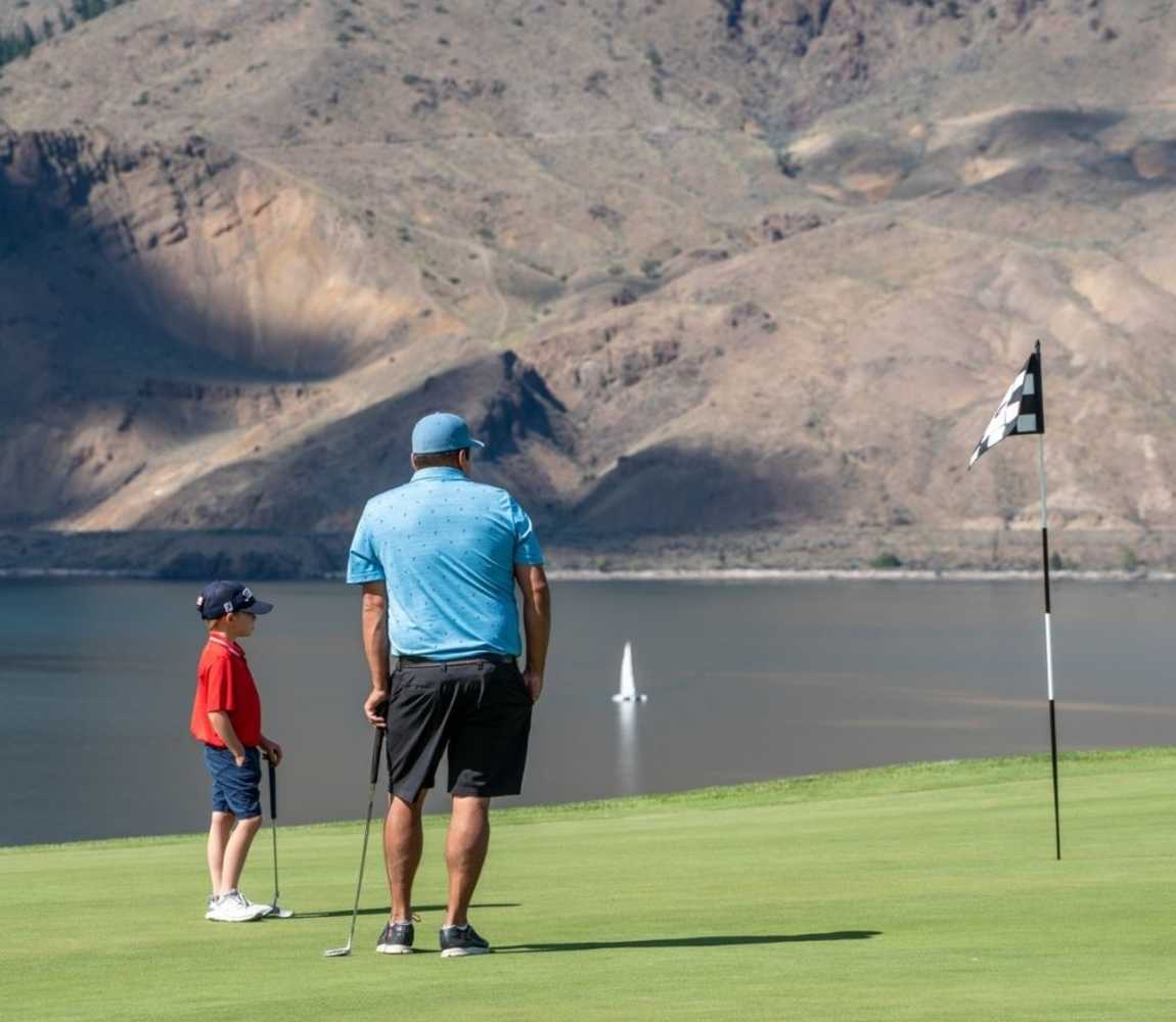 A kid and his dad golfing at Tobiano golf course in Kamloops