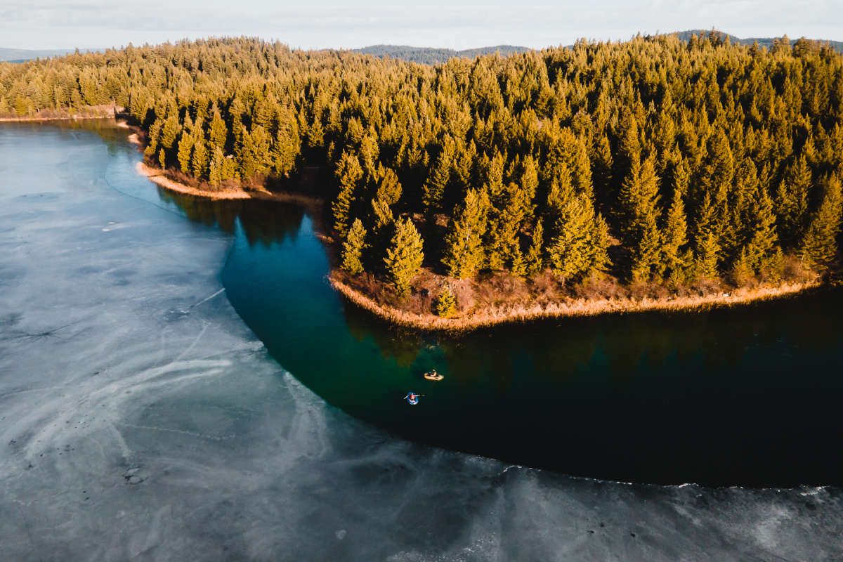 Bird's eye view of a thawing lake with two fishing boats in Kamloops, BC.