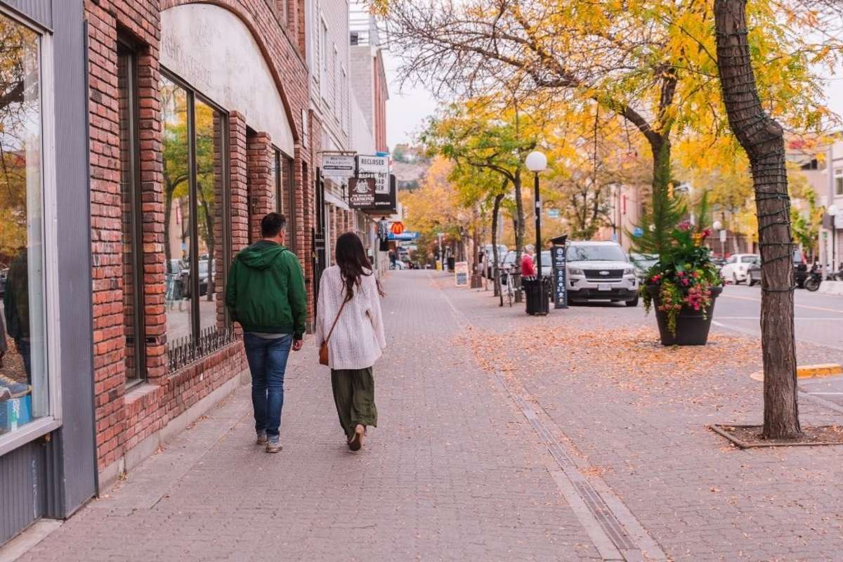 two individuals walking down a street amongst fall coloured trees