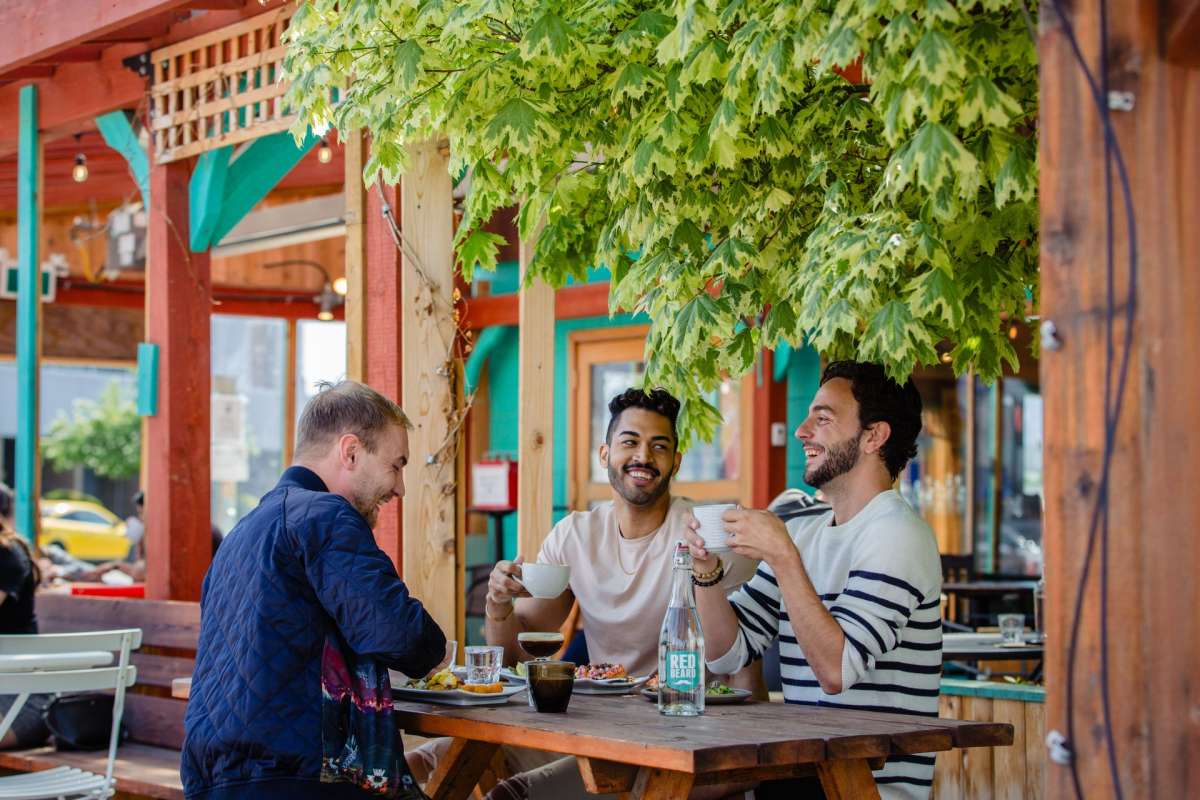 Three men dining and drinking coffee on the Red Beard Cafe Patio located on Kamloops North Shore, British Columbia.