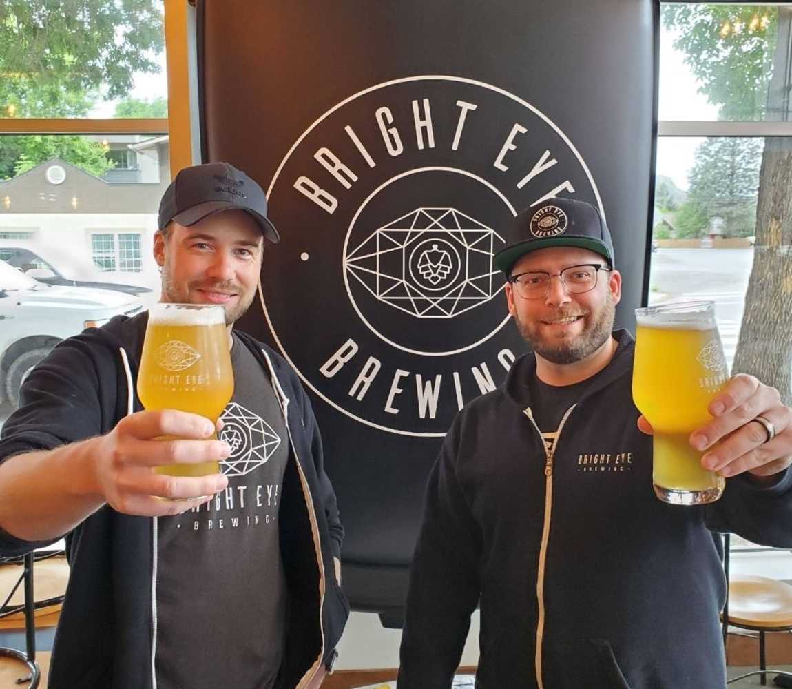 Bright Eye Brewing brewers, Bryan and Tyler, holding up a beer