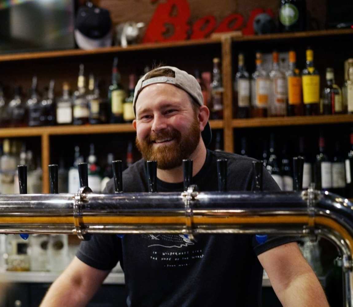 Noble Pig Brewhouse brewer, Nick Murphy, smiling behind the counter