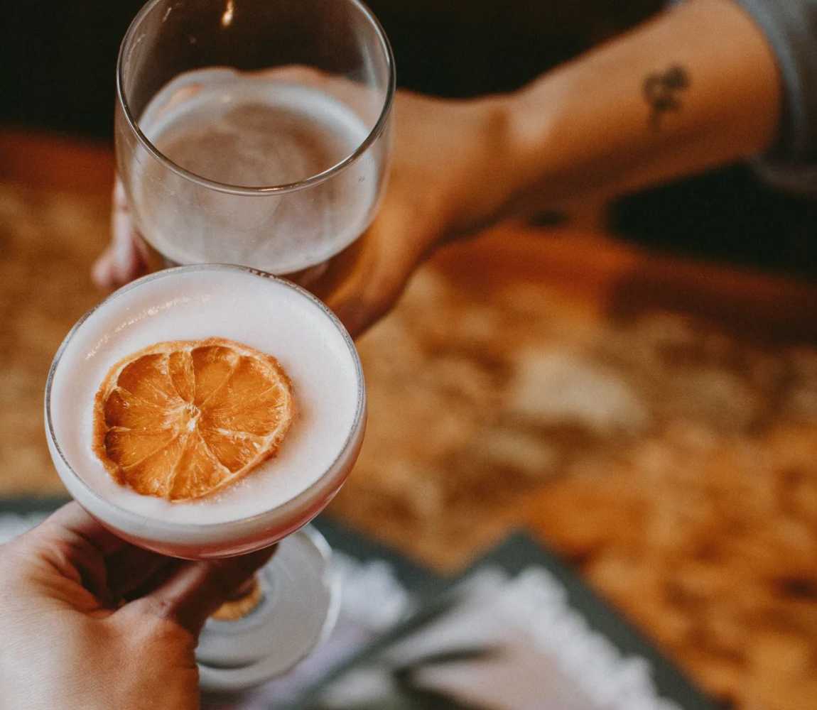 Two people cheers-ing a Gin Lane Drink and Red Collar beer at Red Collar Brewing