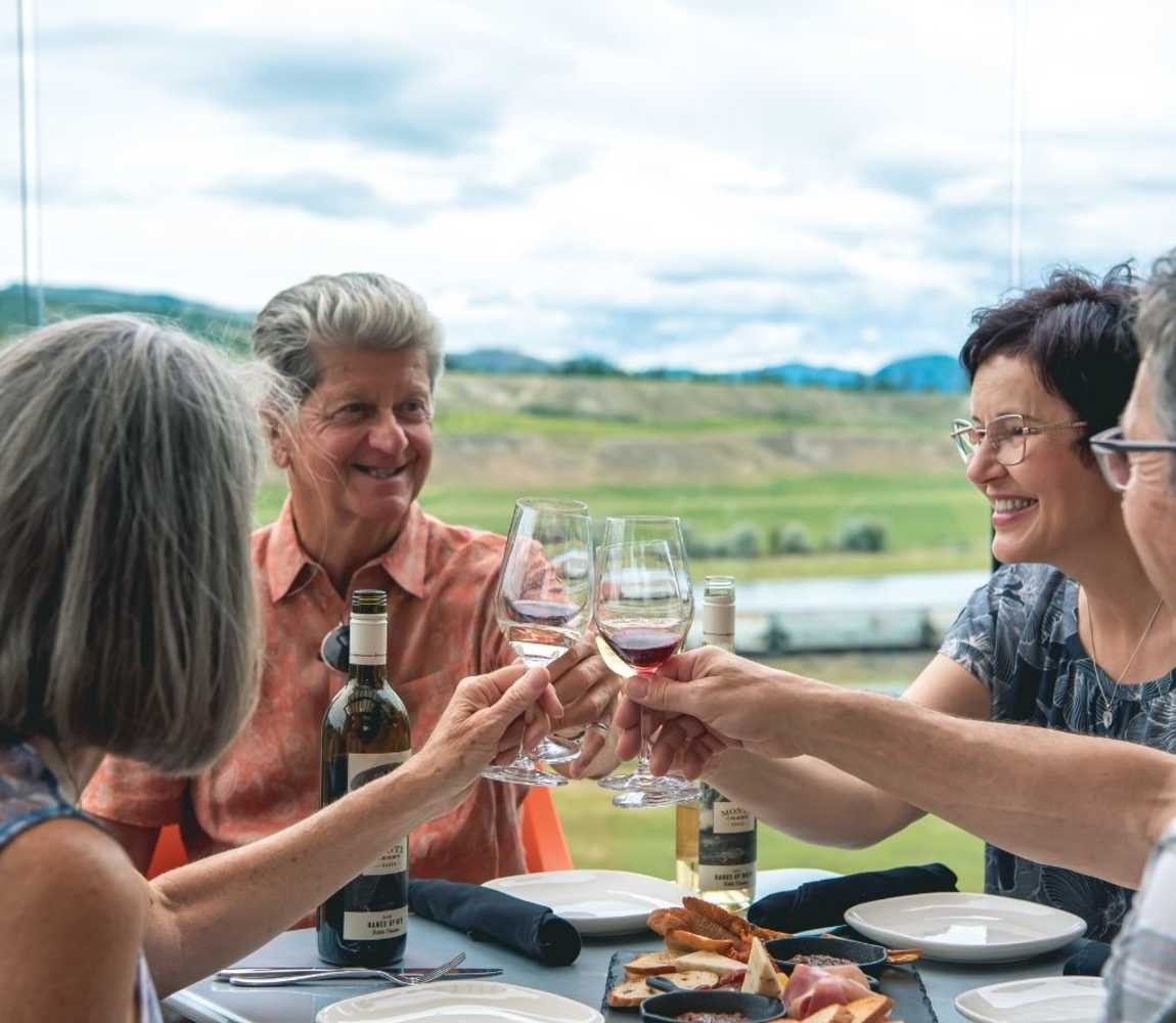 4 individuals on a patio cheersing wine glasses