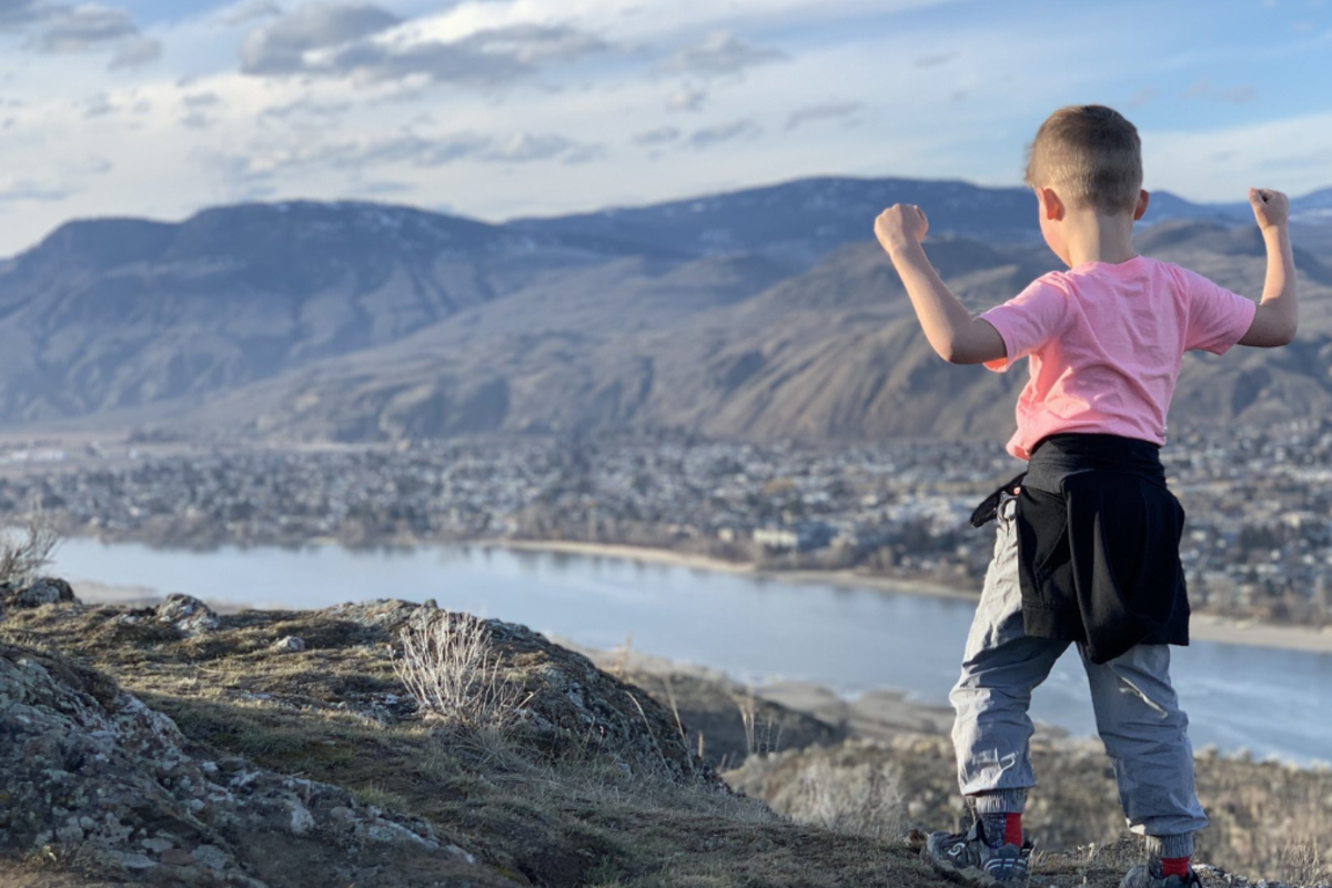 Little boy celebrating his hike to the top of a lookout in Kamloops, BC.