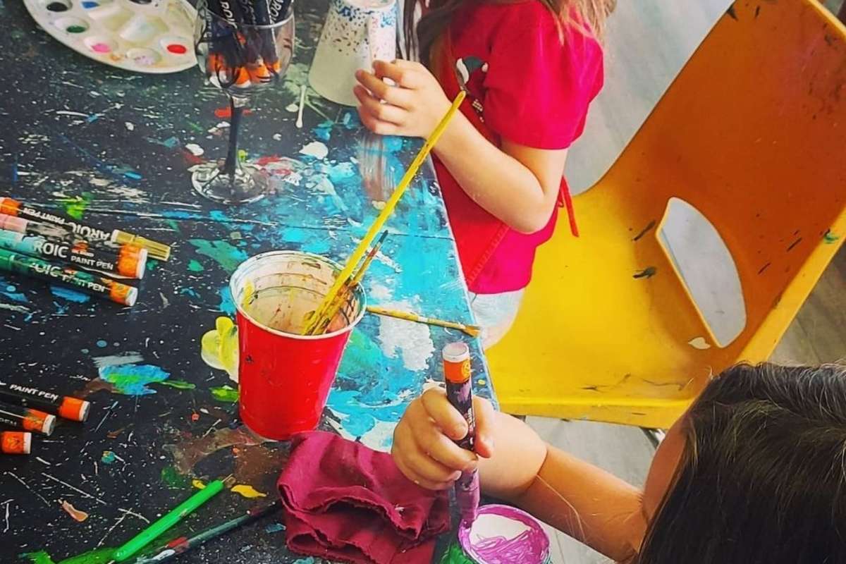 table of bright paint brushes and paint for birthday party