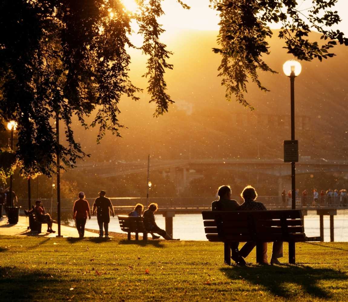 Couples sitting at benches on Riverside Park during summer