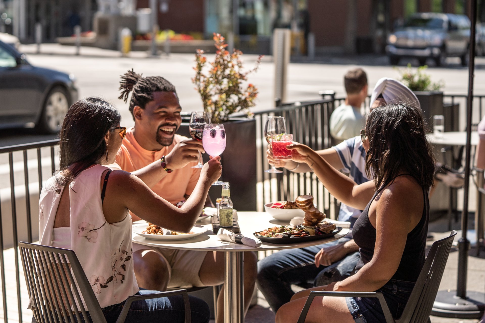 Group of people cheers-ing their drinks on the sunny Cordo Resto + Bar patio located in downtown Kamloops, British Columbia.