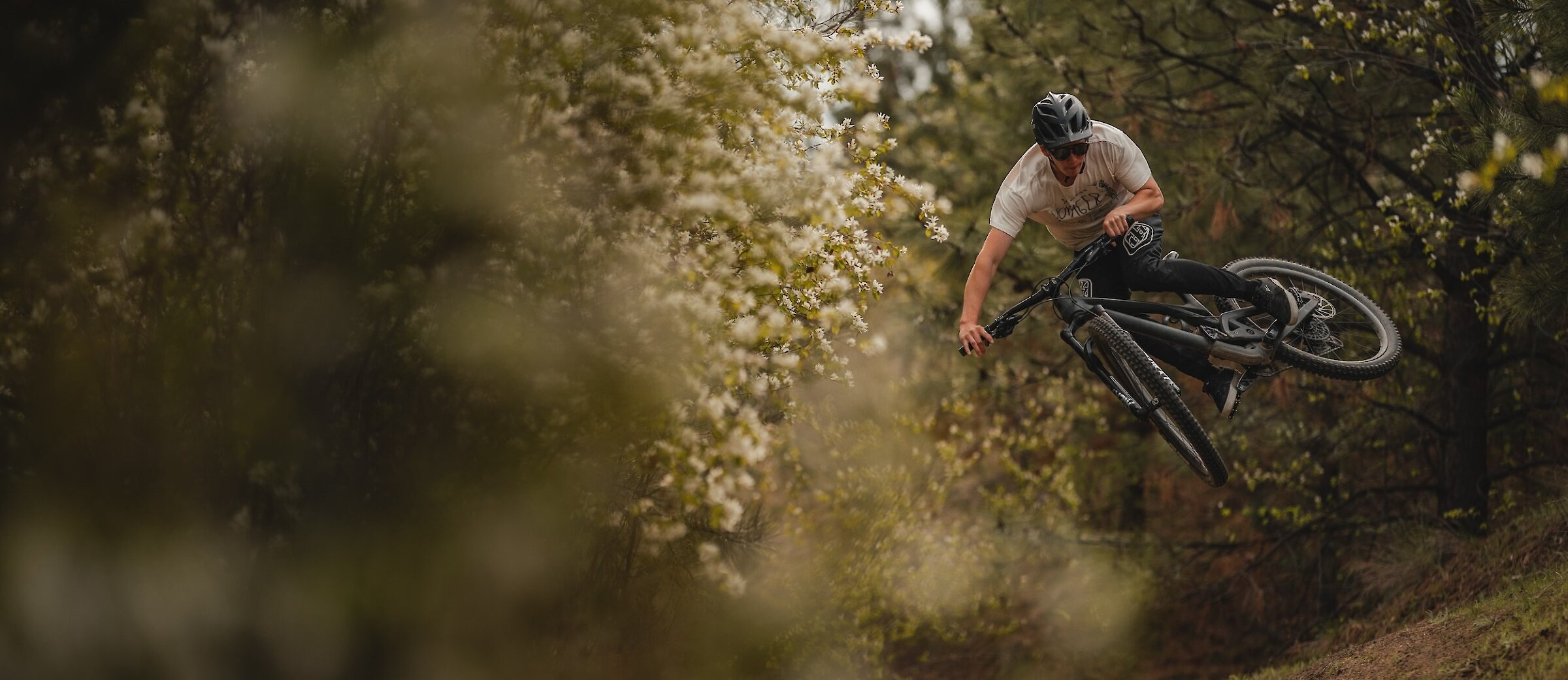 A mountain biker getting air off a jump surrounded by spring flowers in Kamloops, British Columbia.