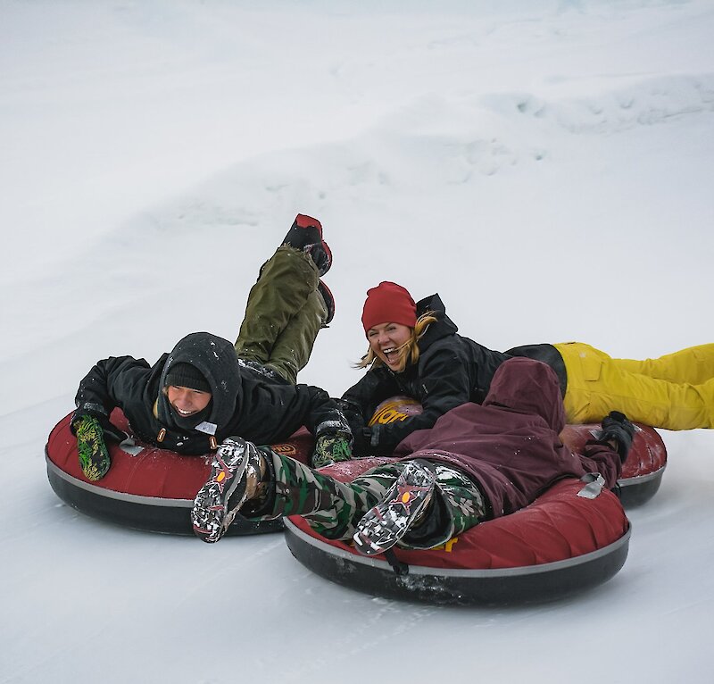 Three people ride tubes down a snowy hill at Harper Mountain, near Kamloops BC