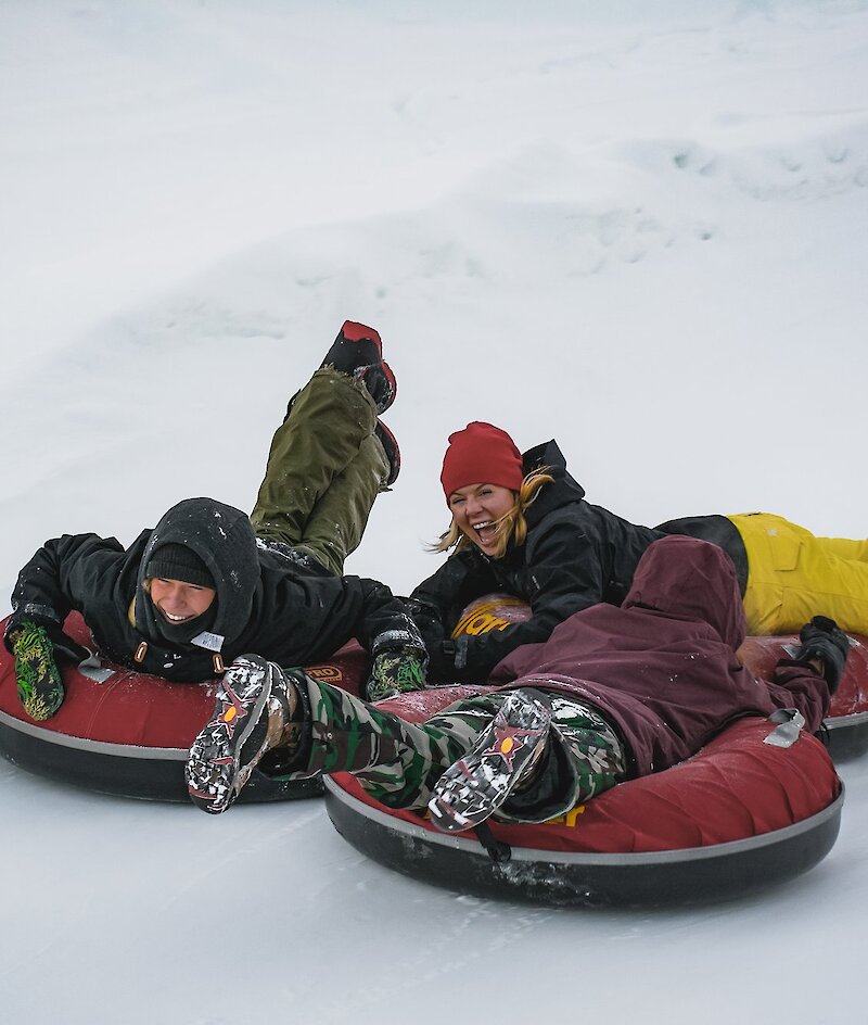 Three people ride tubes down a snowy hill at Harper Mountain, near Kamloops BC