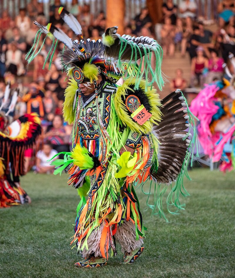 Dancer dressed in vibrant colours at the Kamloopa Powwow at  the Special Events Facility (the Arbour) within Secwepemcúl’ecw, British Columbia.