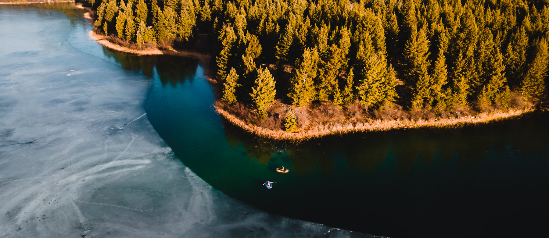 Two fishing boats along the receding ice in a scenic lake near Kamloops, BC.