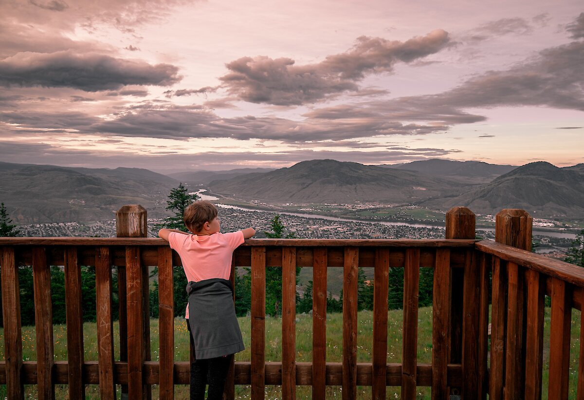 Boy admiring the view of city from Tower Trail lookout at Kenna Cartwright Park in Kamloops, BC.