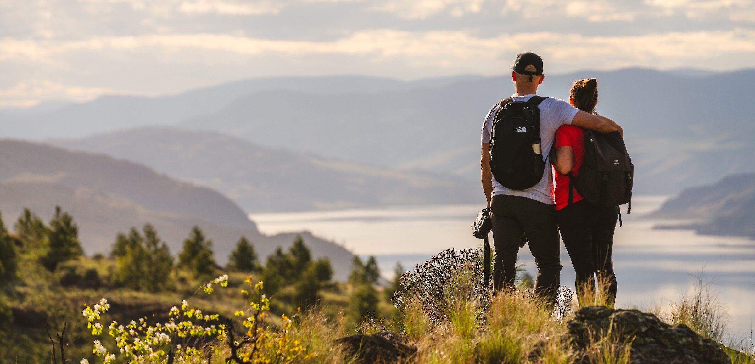 Two hikers admiring the view over Kamloops lake from Kenna Cartwright Nature Park in Kamloops, BC