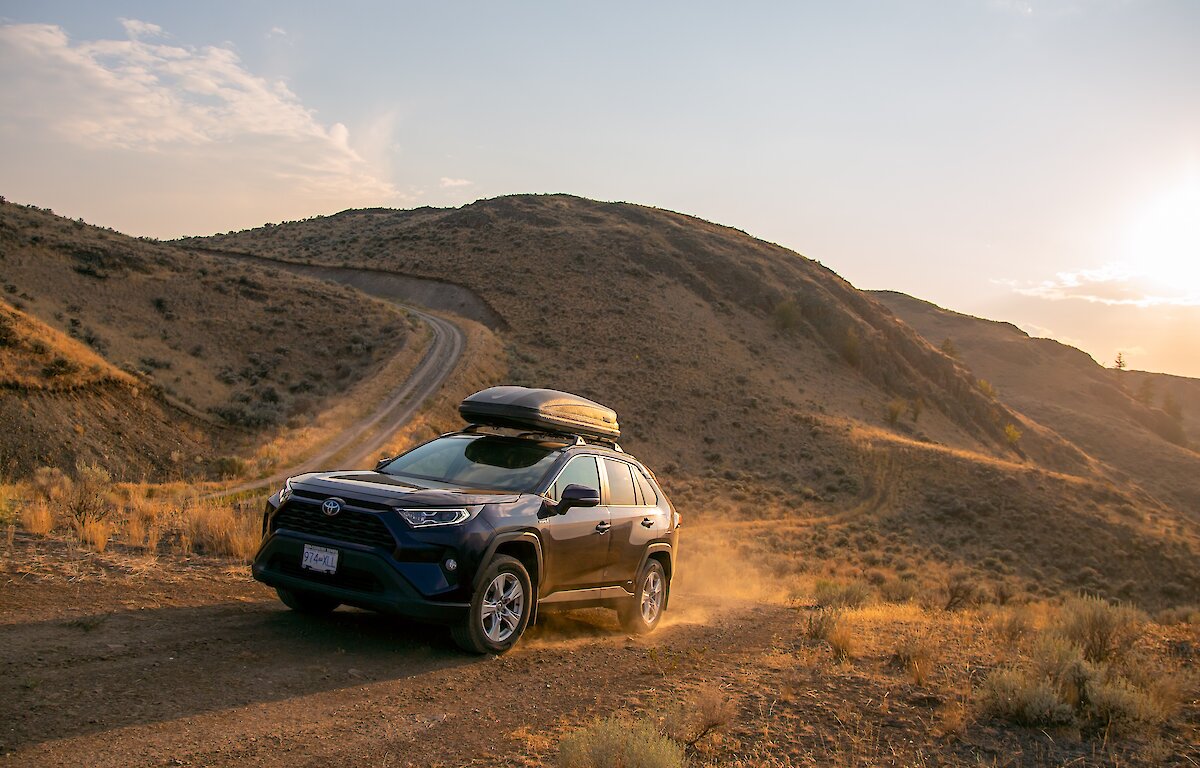 A Rav4 driving up a dirt road surrounded by golden grasslands in Kamloops, BC.