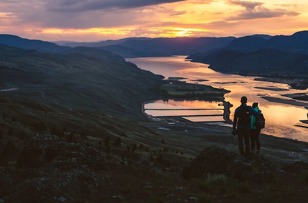 Two anglers in a fishing boat, one netting the fish on the other's line, near Kamloops, BC.