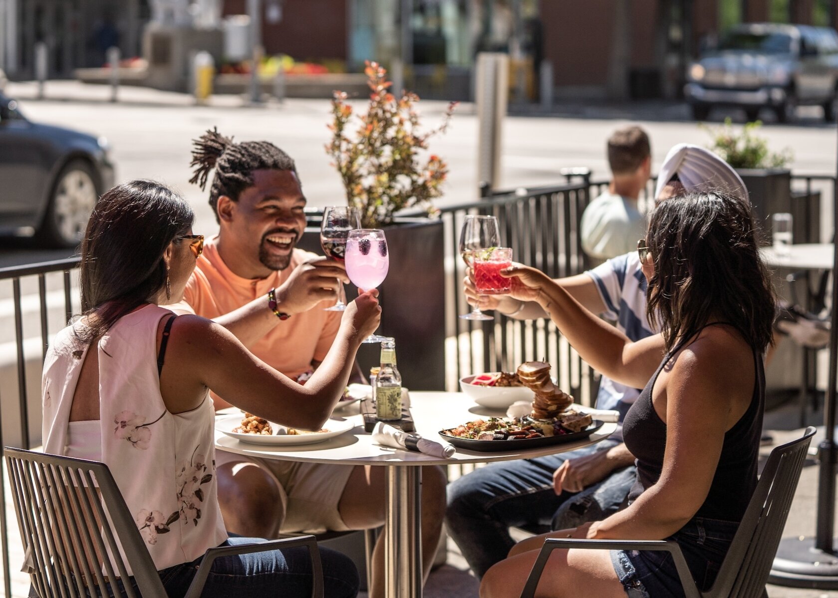 Group of diners on the sunny patio at Cordo Resto + Bar cheer-ings their beverages, located in downtown Kamloops, BC.