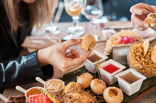 Woman grabbing a piece of food from the share platter at Jadoo Eclectic Indian Cuisine, located in Kamloops, British Columbia.