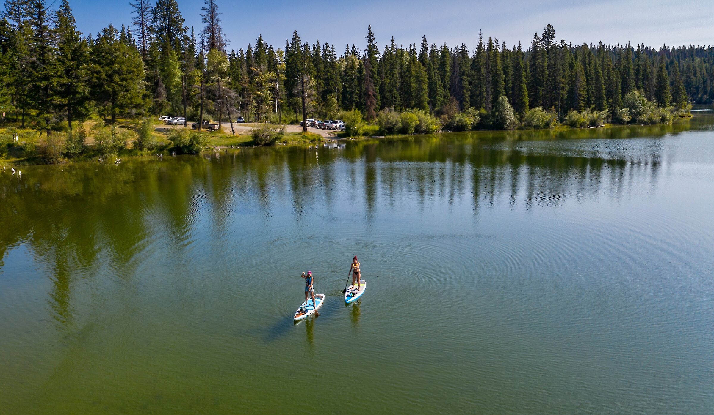 Two paddleboarders on McConnell Lake paddling over the calm waters in Kamloops, BC.