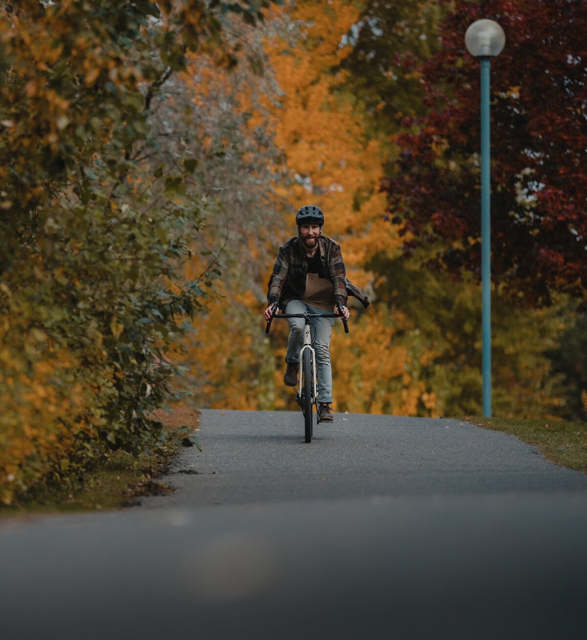 Biker riding along Rivers Trail with fall trees along the trail in downtown Kamloops, BC.