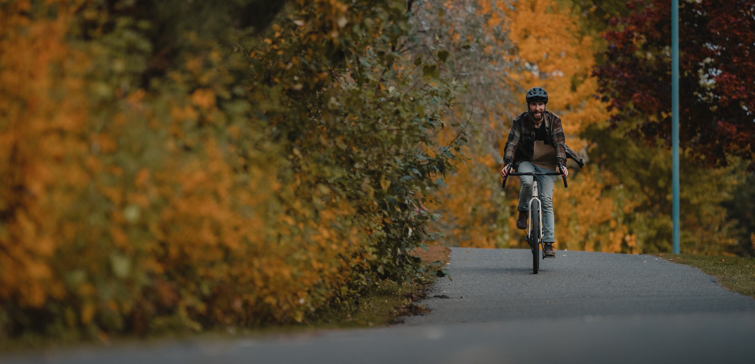 Biker riding along Rivers Trail with fall trees along the trail in downtown Kamloops, BC.