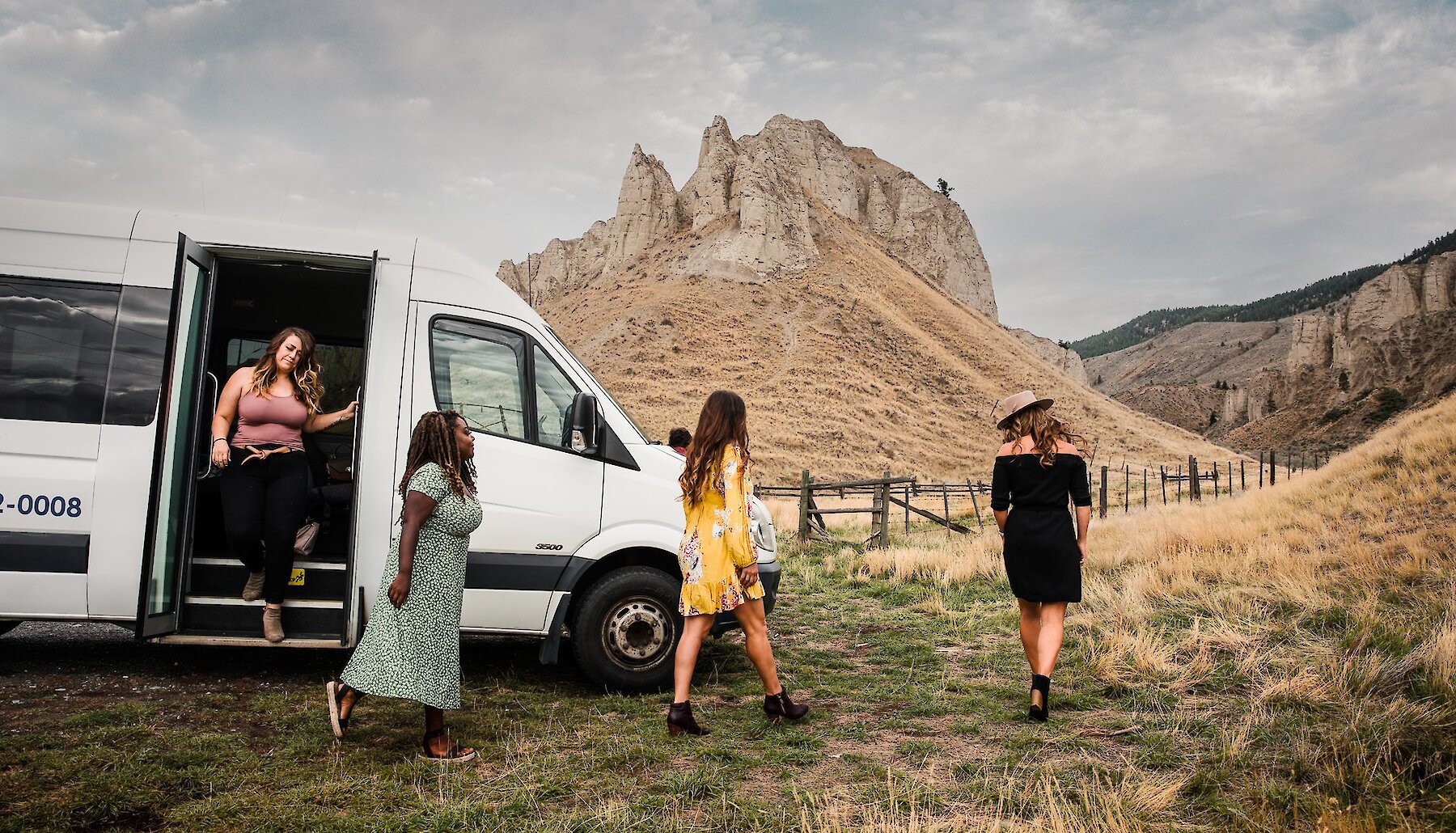 A group of women stepping off a wine tour bus with scenic hoodoos in the background in Kamloops British Columbia.