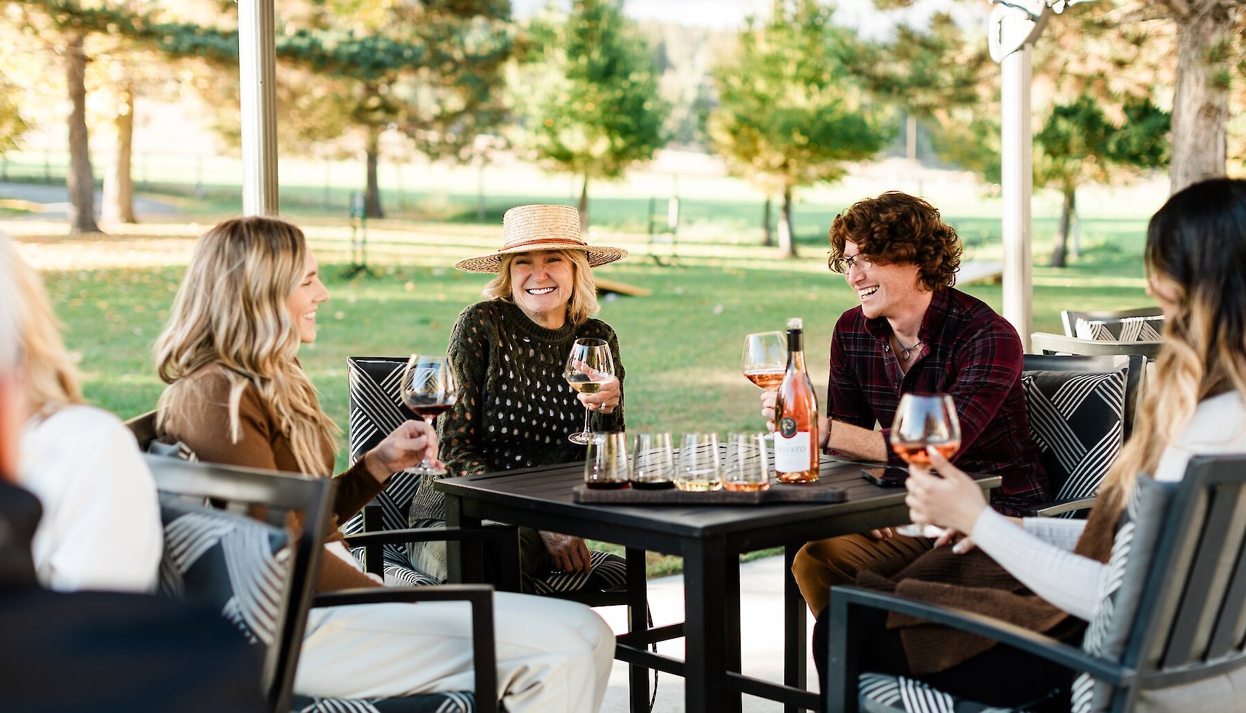 A group sipping on local wines and cider on the sunny patio at Privato Vineyard & Winery and Woodward Cider Co in Kamloops, British Columbia.
