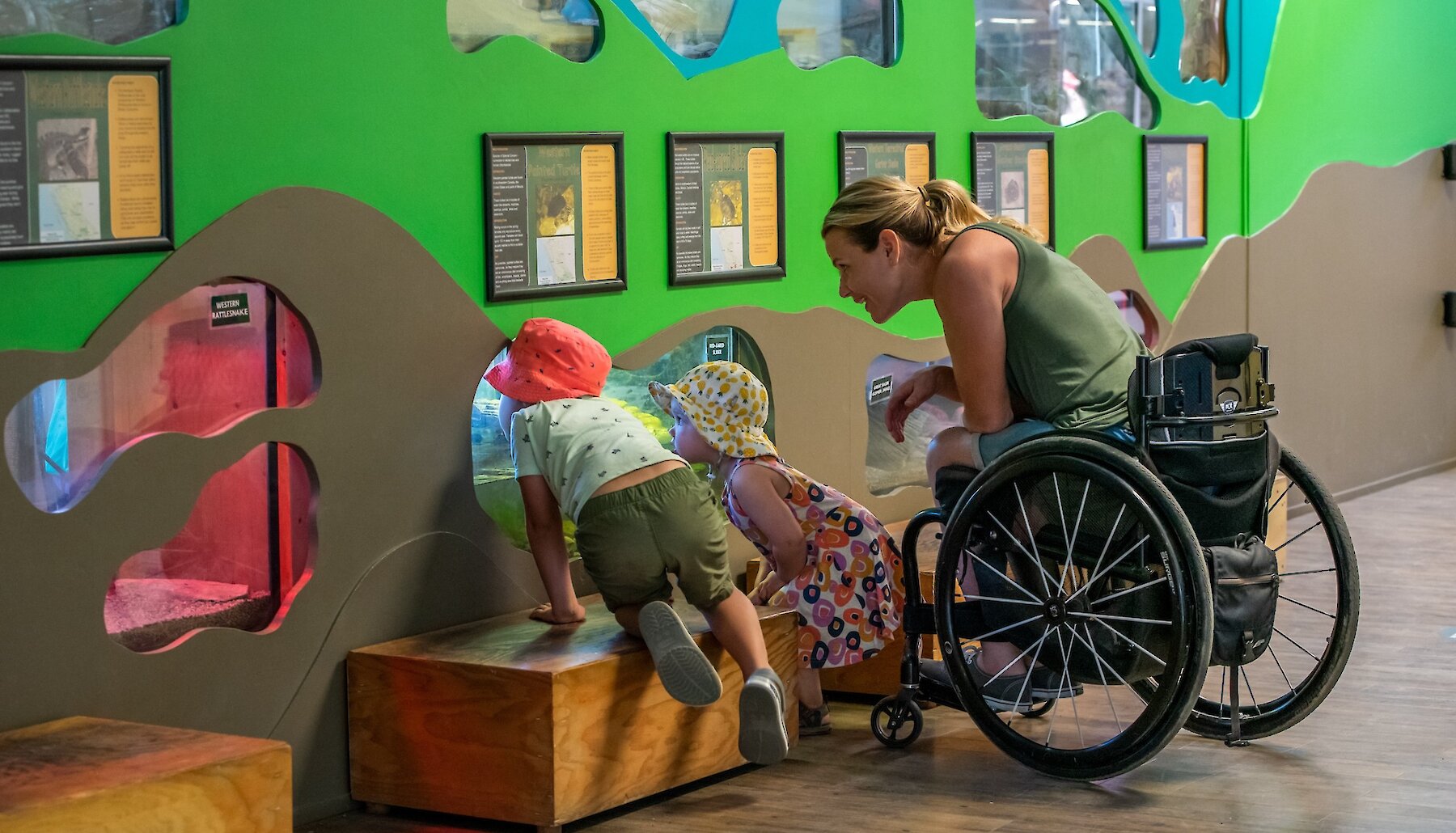A mother and children observing the accessible reptile exhibit at the BC Wildlife Park in Kamloops, British Columbia.