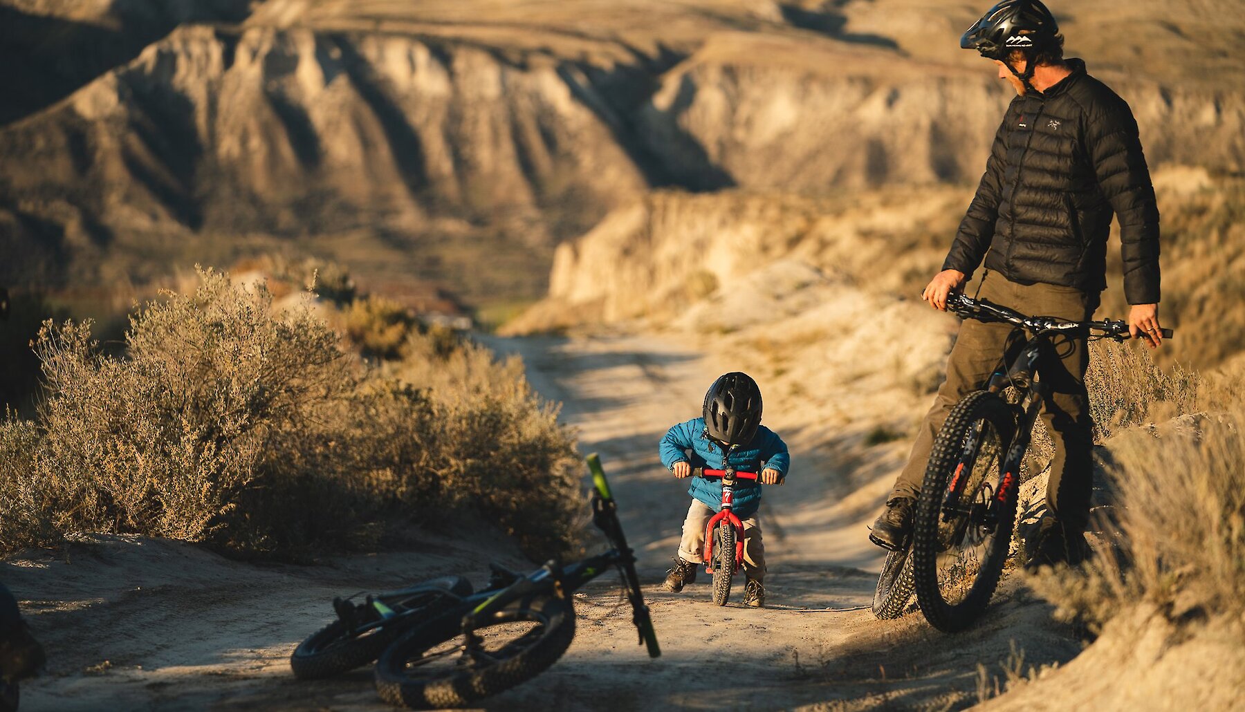 Matt Hunter mountain biking with his son on a Kamloops trail with the iconic hoodoos in the background.