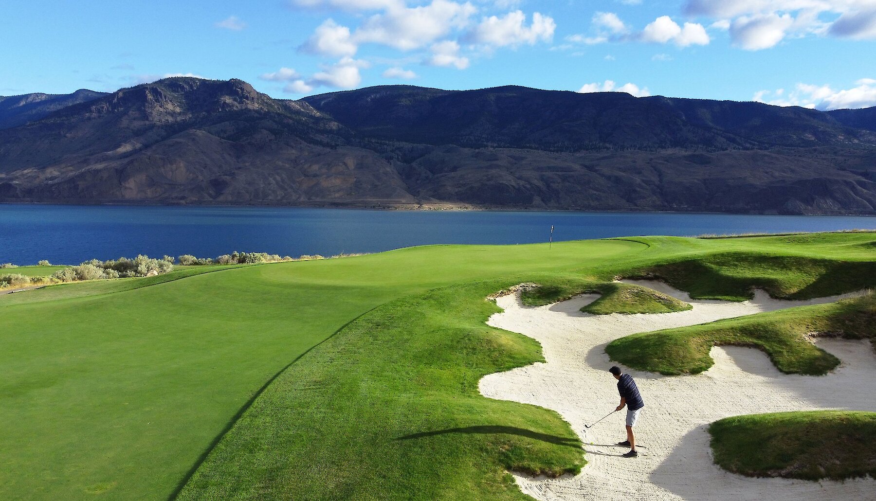 A stunning view of a the Tobiano golf course perched above Kamloops Lake with the BC mountains in the background.