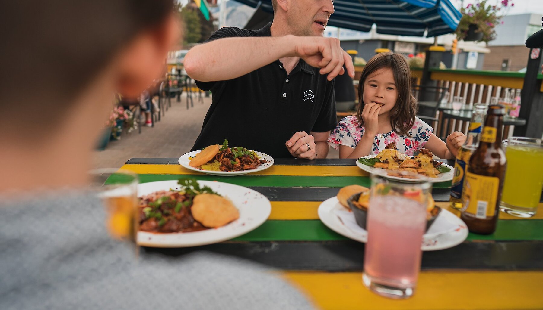 A Father and daughter enjoying the Jamaican Kitchen's family-friendly food located on the North Shore in Kamloops, British Columbia.