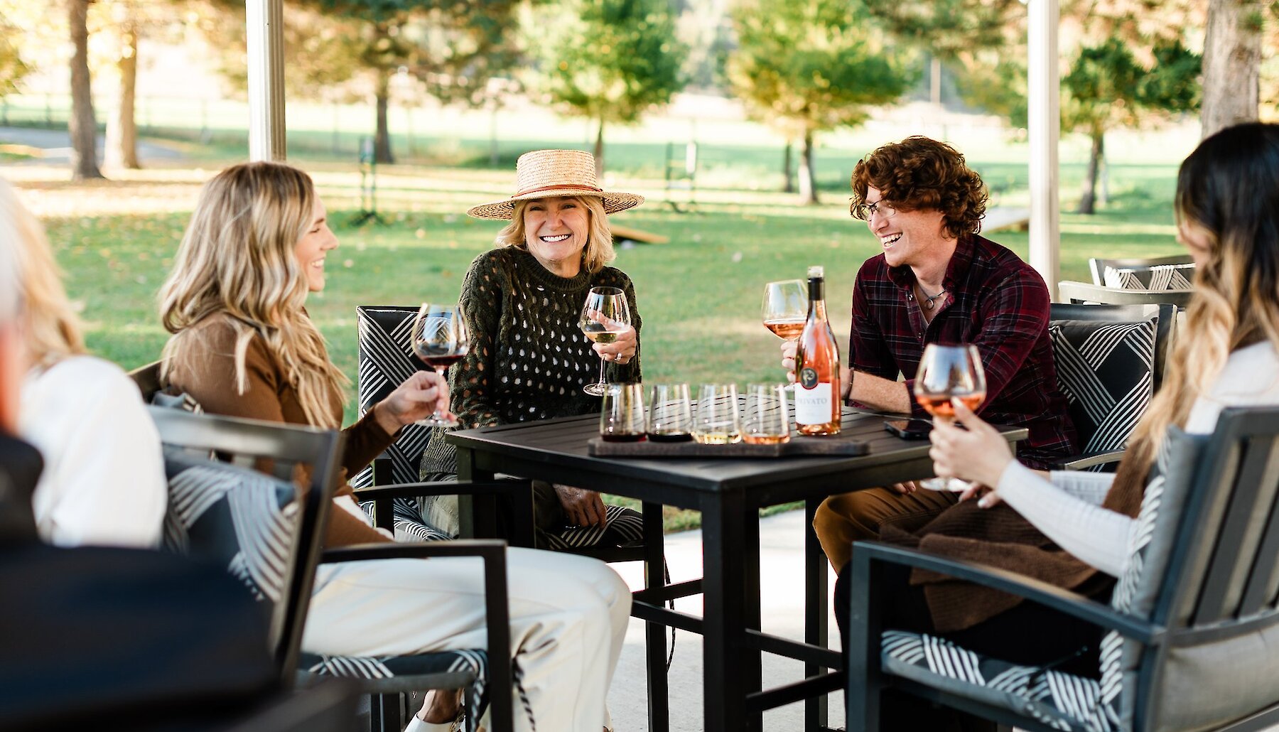 A group of people raising their wine glasses to cheers with local wine on the patio at Privato Vineyard & Winery in Kamloops, British Columbia. 