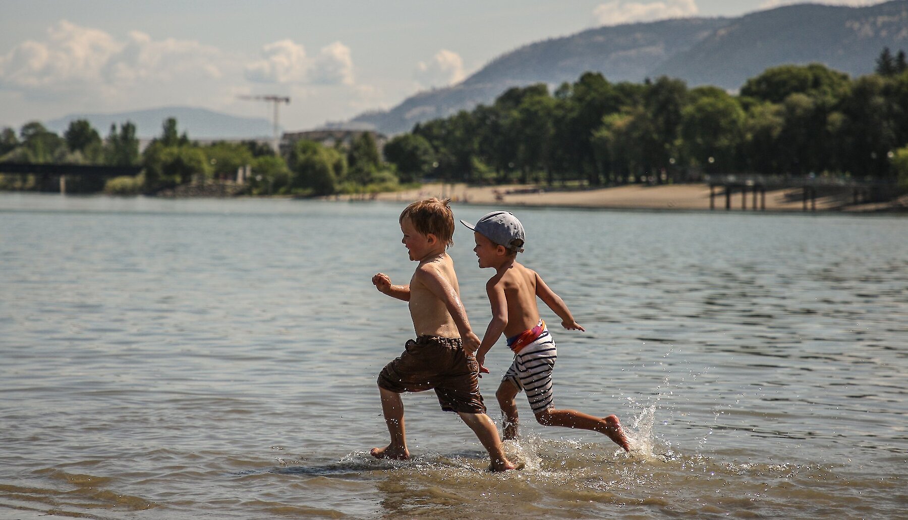 Two boys running into Kamloops Lake at Overlander Beach on the North Shore in Kamloops, British Columbia.