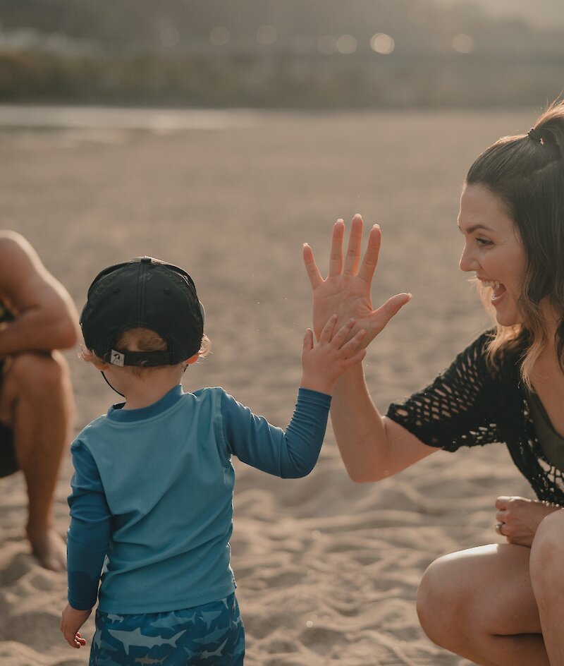 Mom giving a high-five to her son at the Overlander Park beach at Kamloops, BC.