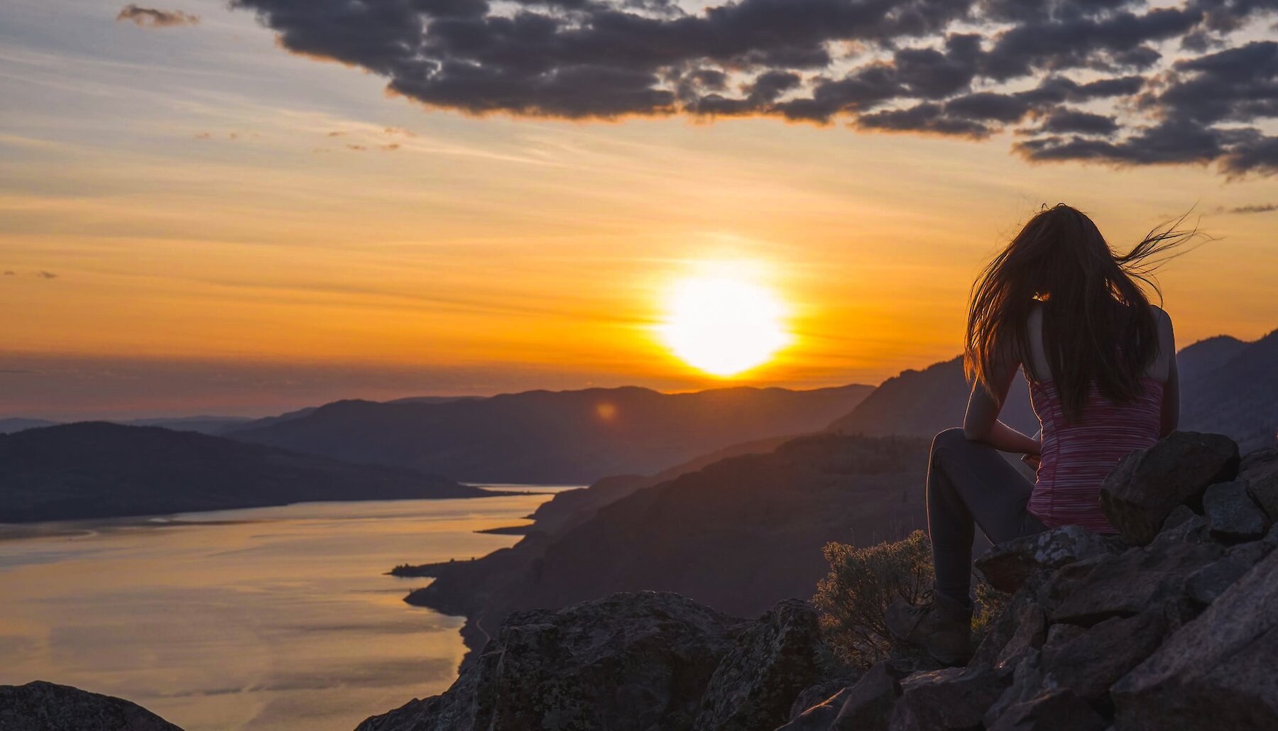 Woman watching the sunset from Battle Bluff over Kamloops Lake.