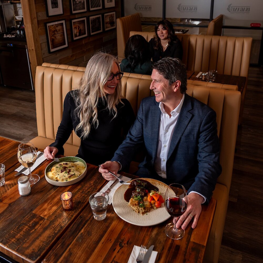 A couple smiling at each other as they enjoy their meals at Isagani Farm-to-Table in Kamloops, BC.